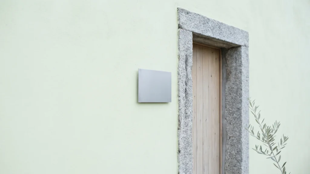 Targa metallica vuota accanto alla porta di un appartamento con stipite in granito sardo